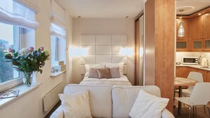 A modern bedroom with a bed, a sofa, a dining area, and a kitchen. - Warsaw Apartments Magnolie (Warsaw)