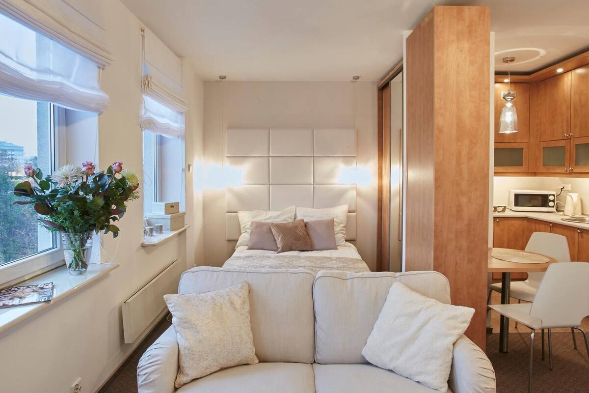 Ein modernes Schlafzimmer mit Bett, einer Couch, einem Essbereich und einer Küche.