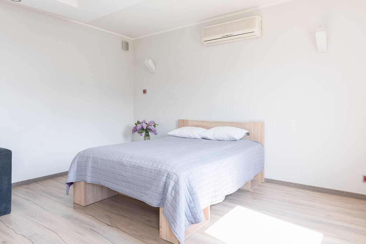Ein Schlafzimmer mit einem Bett, einem Holzkopfteil, weißen Wänden und einem Holzboden.