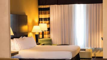 A hotel room with a bed, two bedside lamps, a chair, a nightstand, and a window with curtains.
