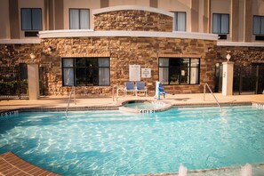 Une piscine avec un mur en pierre et un panneau indiquant qu’il est interdit de plonger.