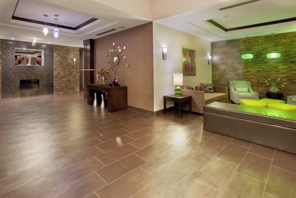 A spacious lobby with a fireplace, seating area, and decorative wall art. - Holiday Inn Express & Suites Houston NW/Beltway 8 West Road by IHG (Houston)