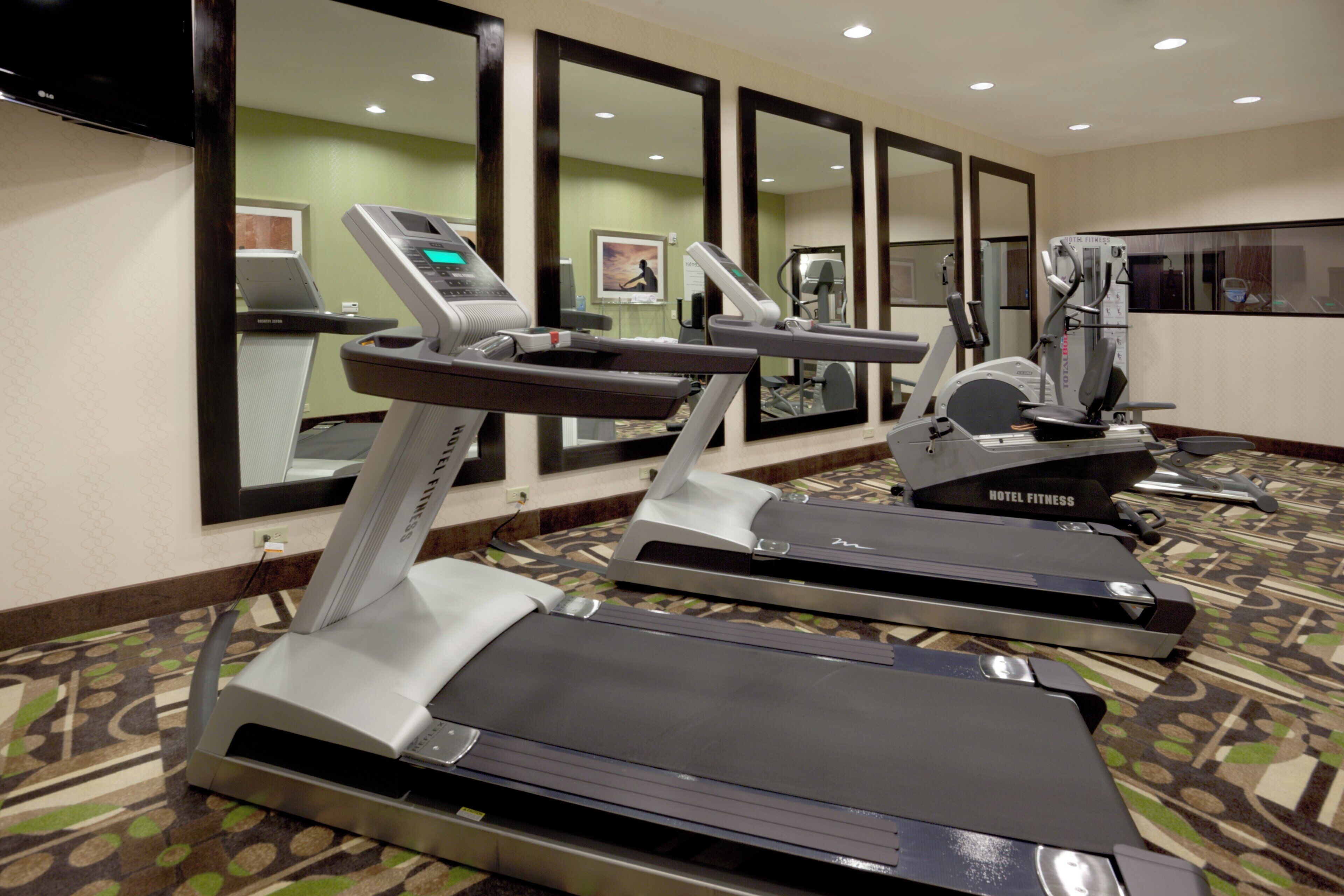 A hotel fitness center with treadmills, a stationary bike, and a rowing machine.