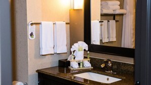 A bathroom with a sink, mirror, towel rack, and toiletries.