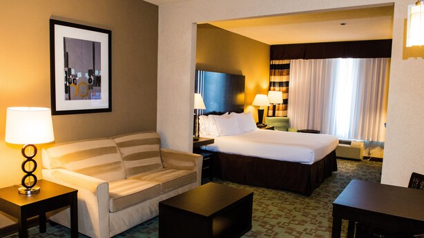 A hotel room with a bed, a sofa, a coffee table, and a desk.