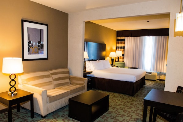 Habitación de hotel con cama, sofá, mesa de centro y escritorio.