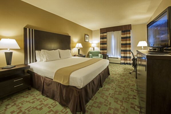Habitación de hotel con una cama grande, dos mesitas de noche con lámparas, una televisión, un escritorio con silla y una ventana con cortinas.