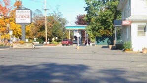 A street view with a sign for Elmwood Lodge, a gas station, and a building with a 'Dine' sign. - Elmwood Motor Lodge (Boscawen)