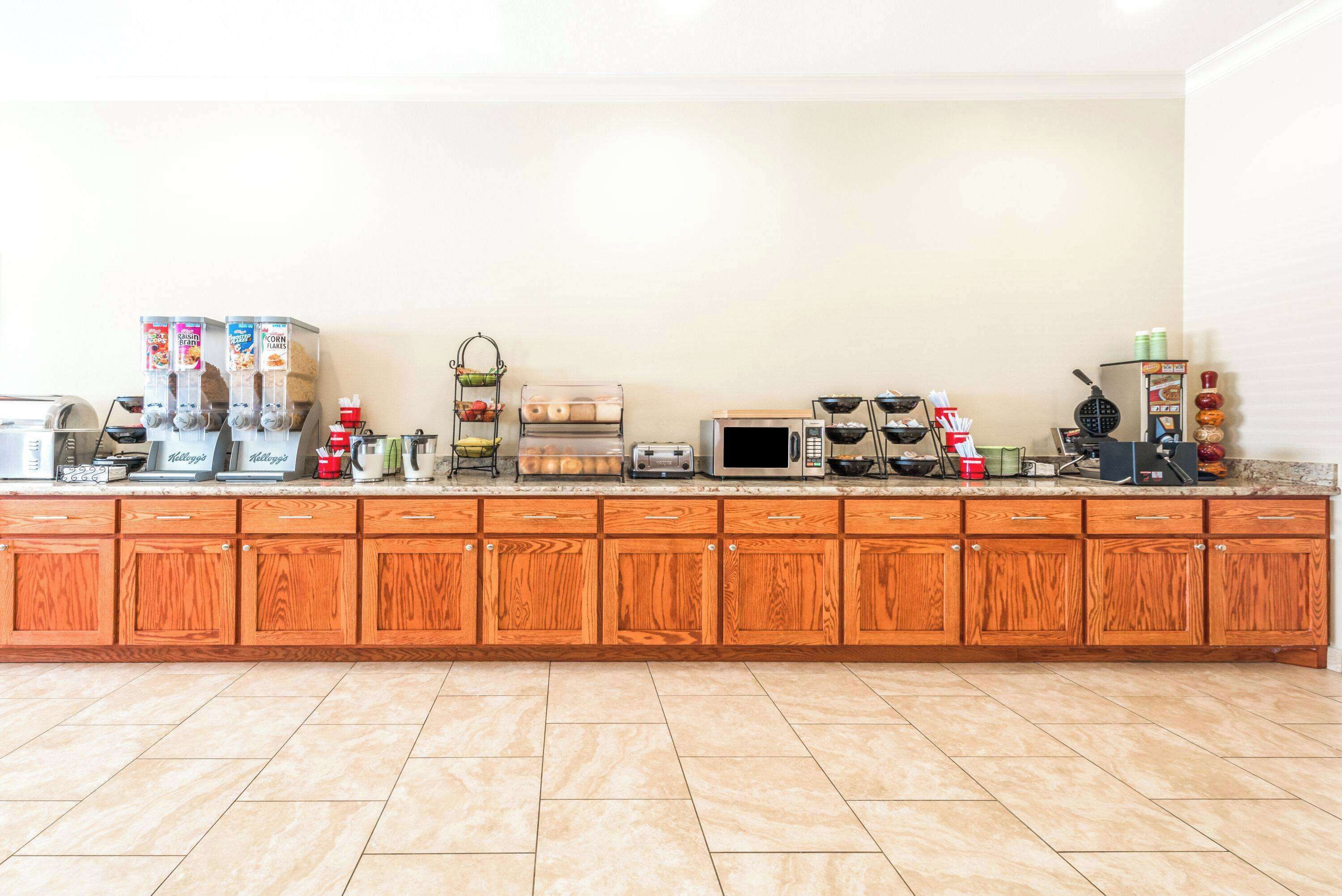 Una cocina con armarios de madera, microondas, tostadora y diversos electrodomésticos.