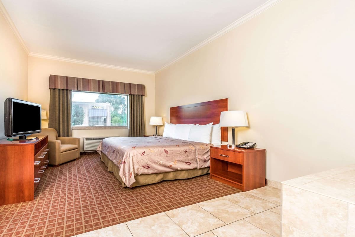 Une chambre d’hôtel équipée d’un lit, d’une télévision, d’un bureau, d’une chaise, d’une lampe et d’un téléphone.