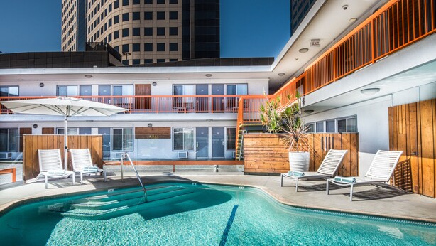 A rooftop pool area with lounge chairs and a large umbrella. - The Tangerine - A Burbank Hotel (Burbank)