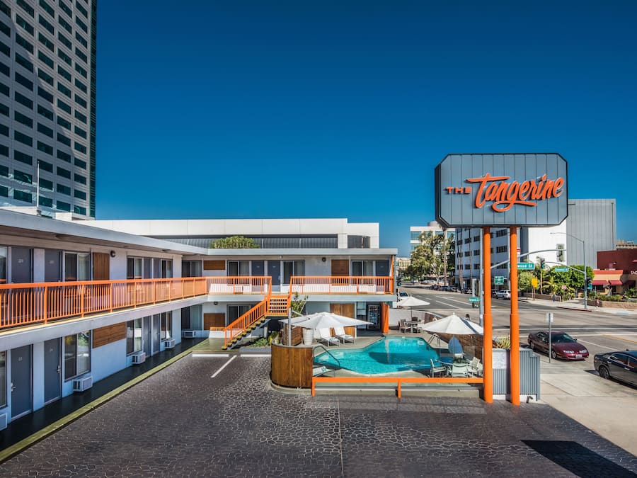Un motel con piscina, asientos exteriores y un letrero que dice "The Tangerine".