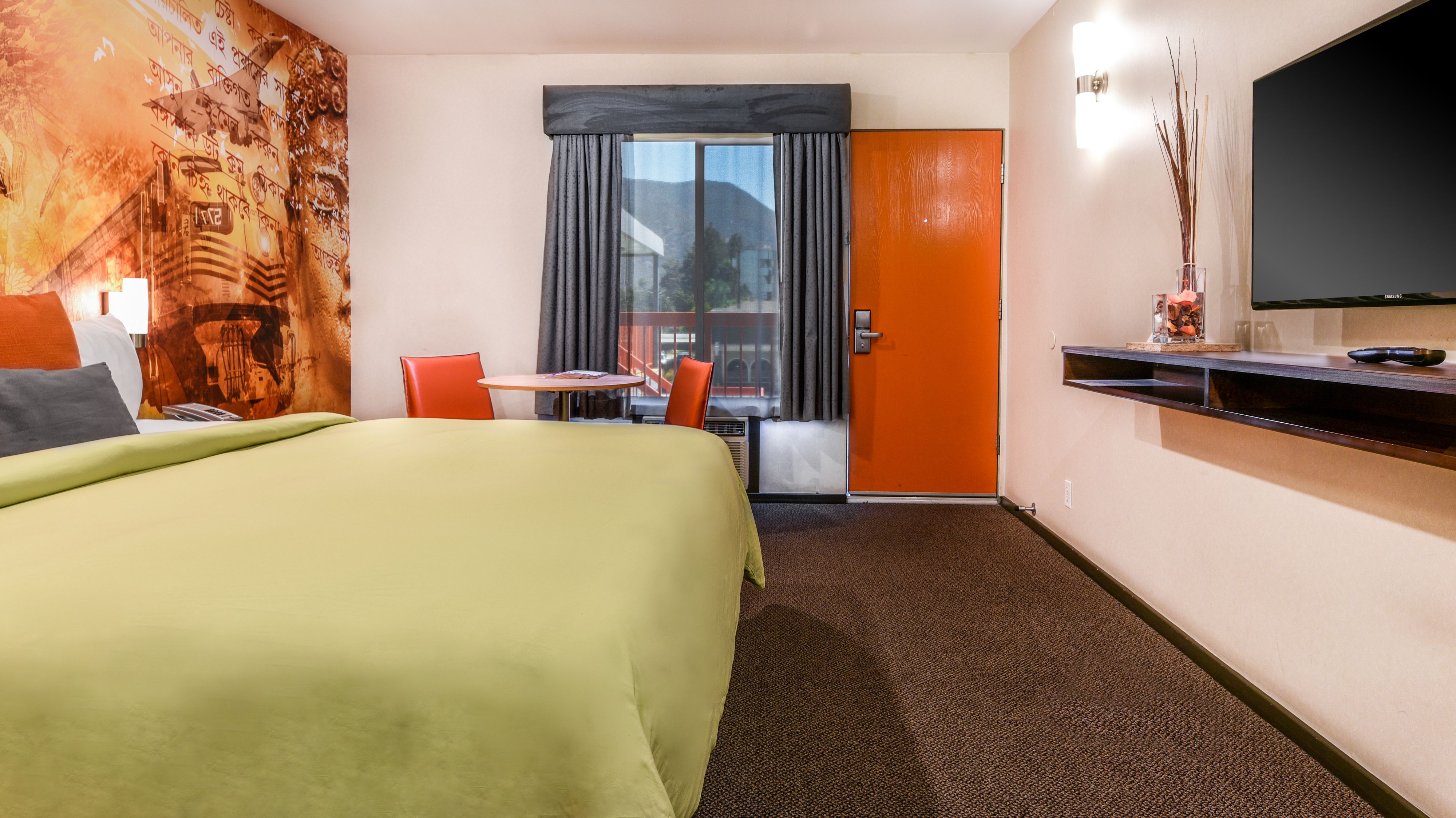 A hotel room with a bed, a desk, a chair, a television, and a window with curtains.