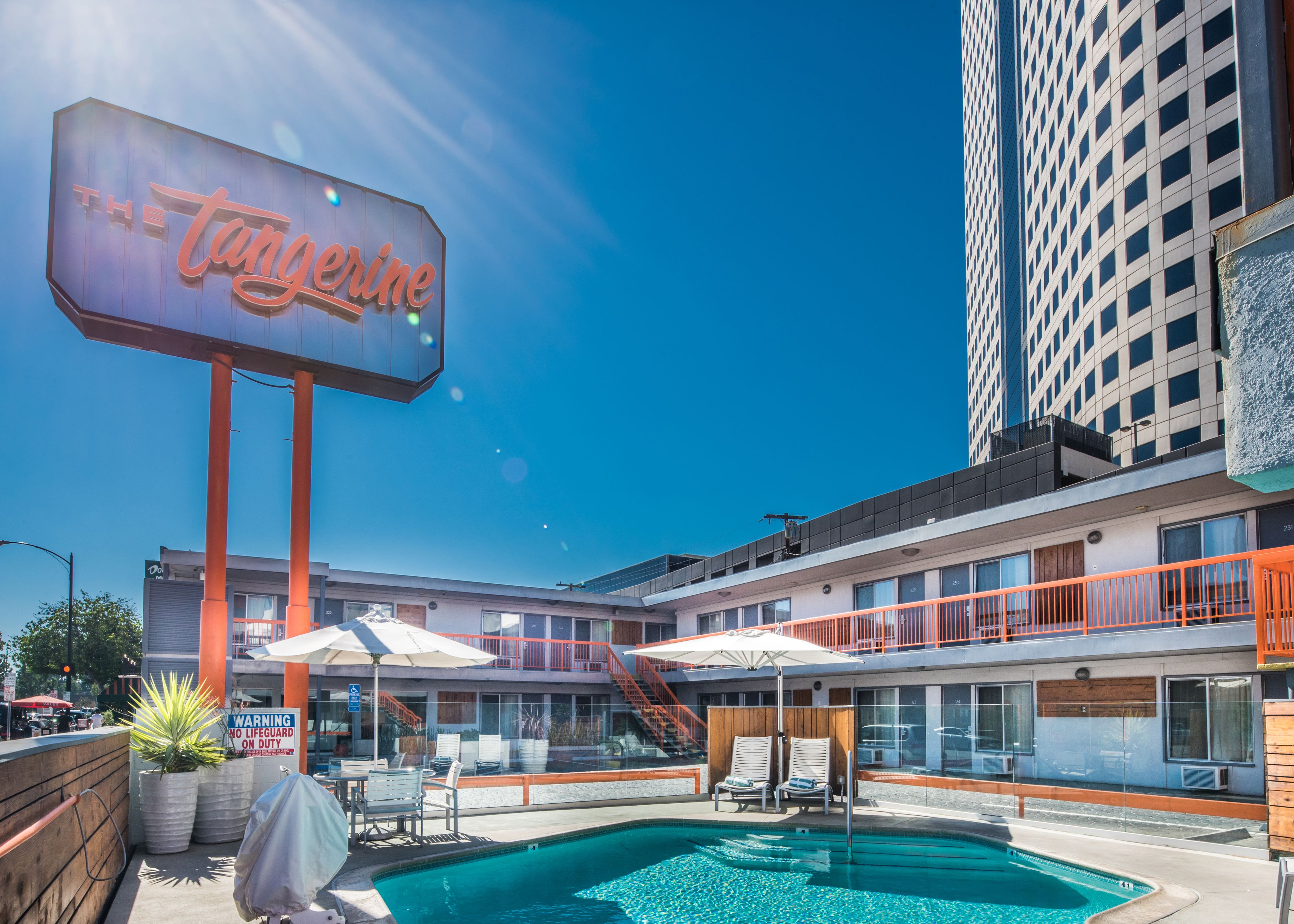 A hotel with a pool area, outdoor seating, and a large neon sign.