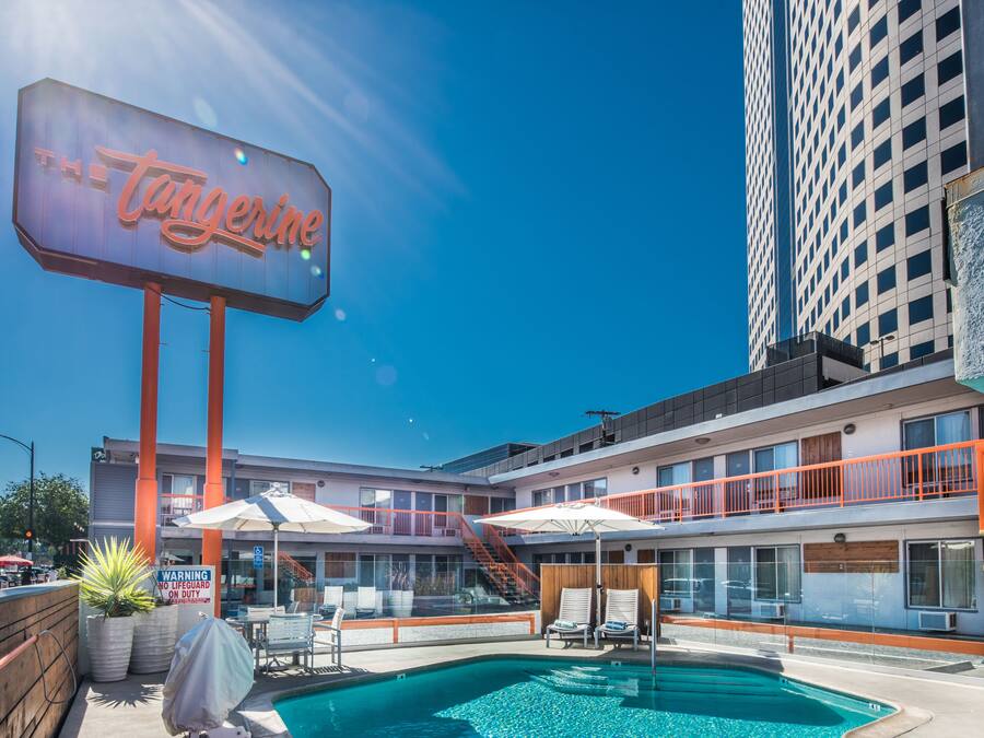 A hotel with a pool area, outdoor seating, and a large neon sign.