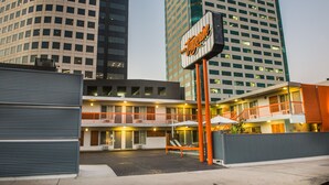 A hotel with a signboard, a balcony, and a modern building in the background. - The Tangerine - A Burbank Hotel (Burbank)