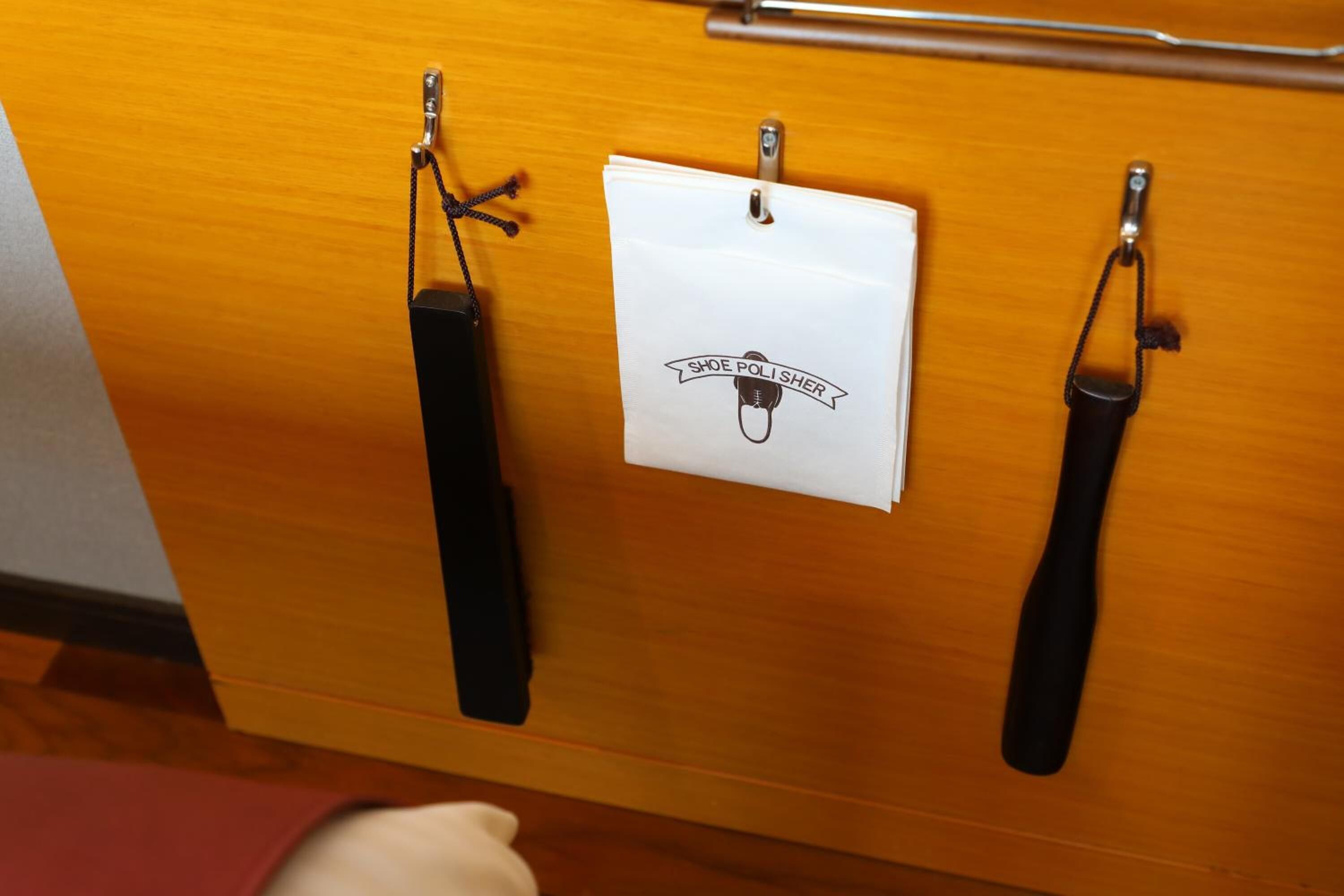 Eine Holztür mit zwei schwarzen Griffen und einem weißen Schild mit dem Logo für Schuhcreme.