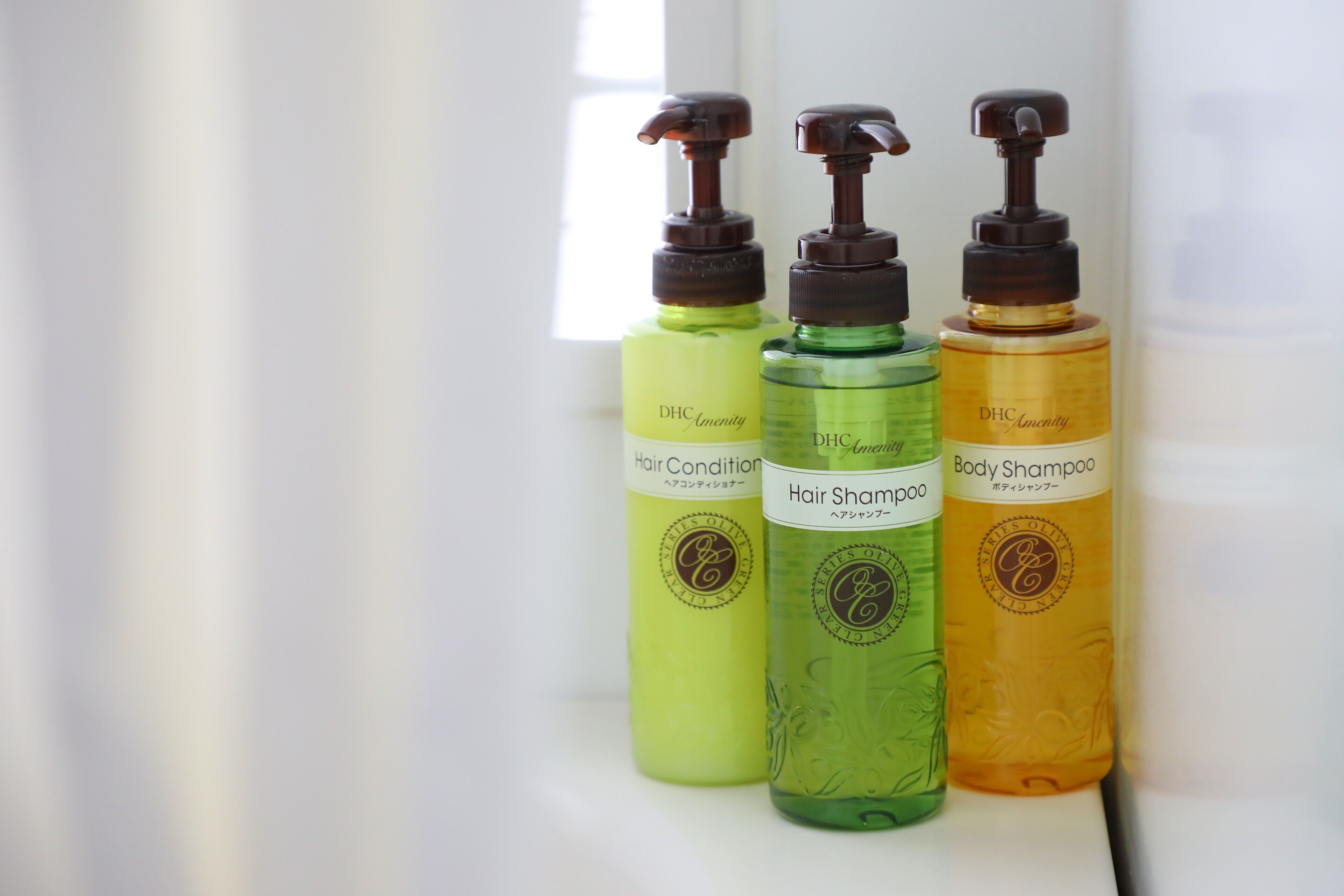 Drie flessen haar- en verzorgingsproducten voor lichaam en huid op een plank.