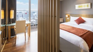 Een hotelkamer met een groot bed, een bureau en uitzicht op de stad.