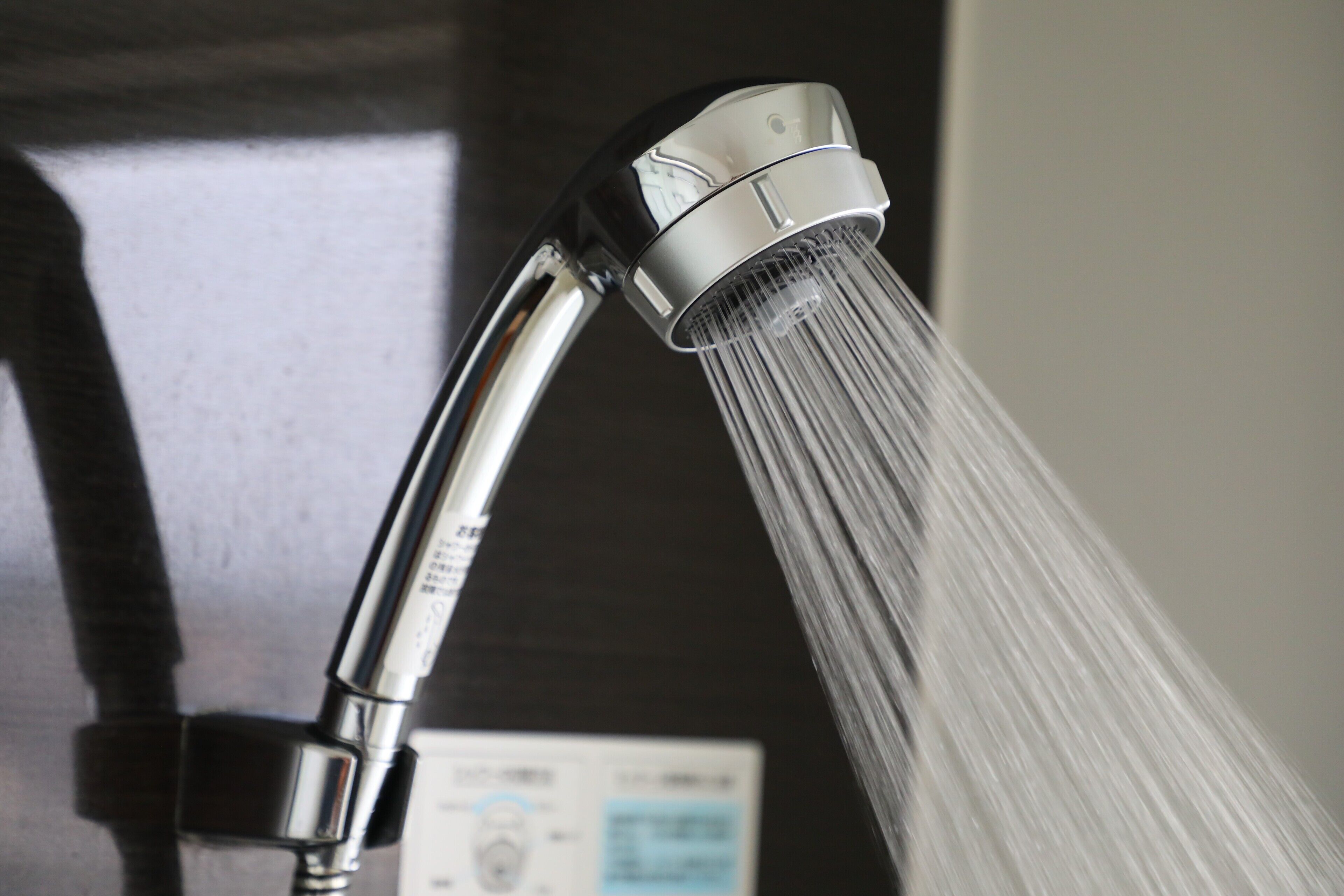 A chrome faucet with water flowing from it, a control panel, and a dark background.