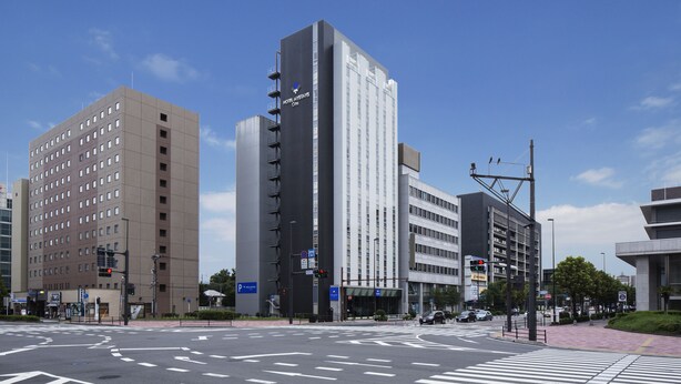 Een modern hotel met meerdere verdiepingen, een opvallende ingang en een heldere lucht.