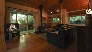 A cozy living room with a fireplace, a sofa, and a television. - Cottages at Monreale (Olinda)