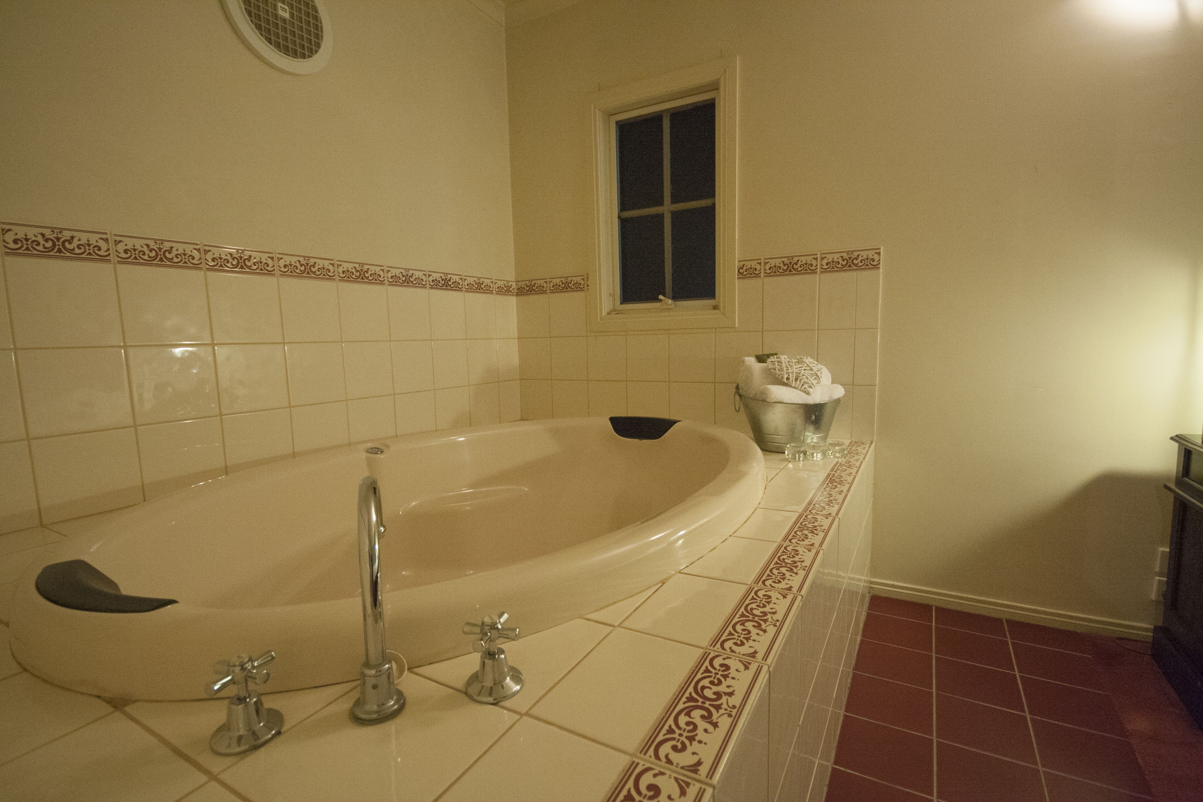 A bathroom with a freestanding bathtub, a window, and a decorative tile border.