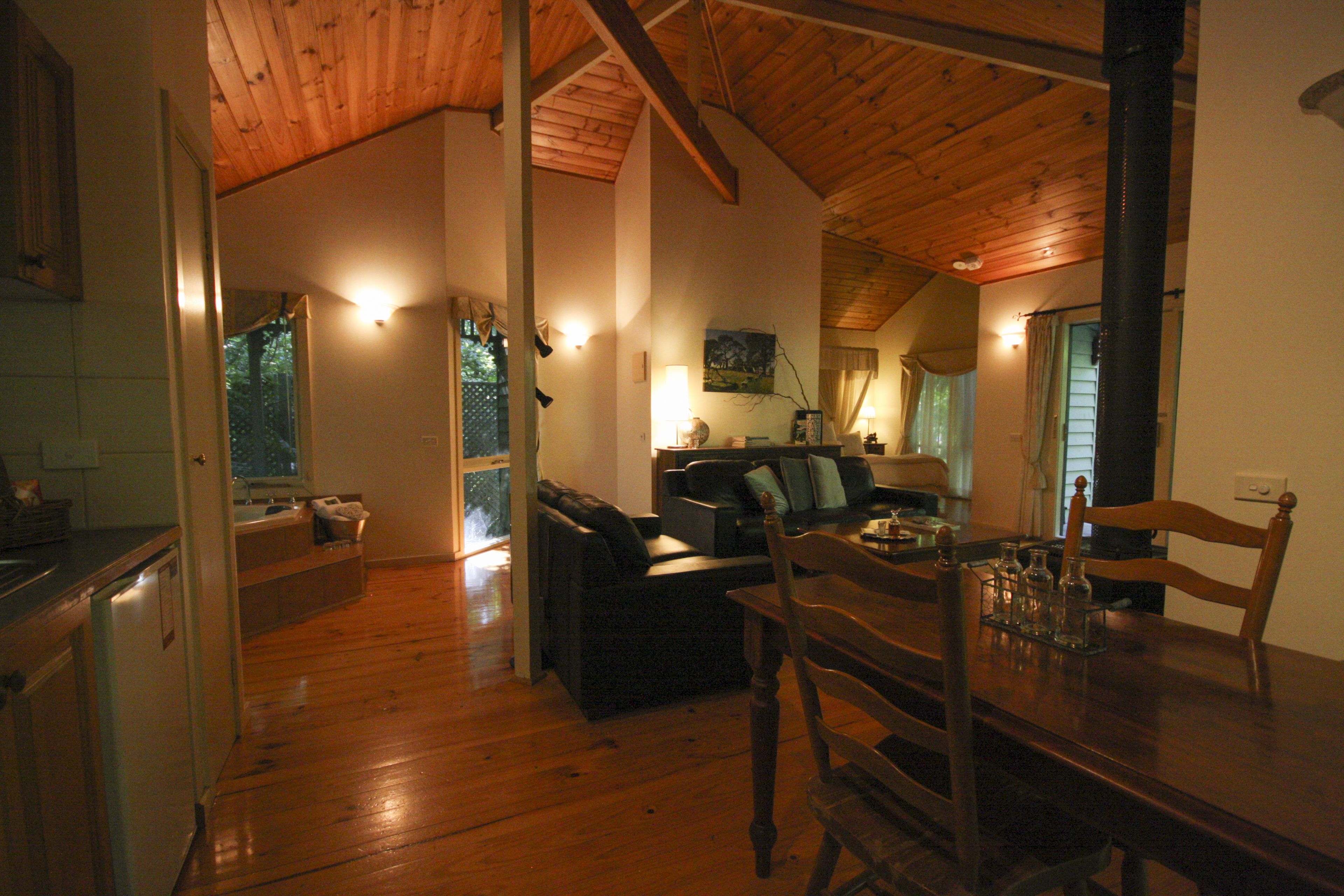 A spacious living area with a wooden ceiling and a dining table set for four.