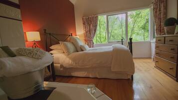 A bedroom with a bed, a dresser, a lamp, and a window with curtains.