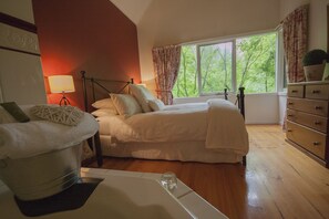 A bedroom with a bed, a dresser, a lamp, and a window with curtains. - Cottages at Monreale (Olinda)