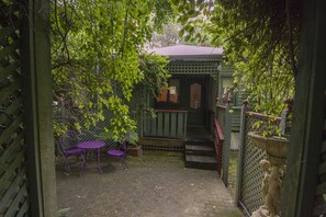 A covered outdoor seating area with a table and chairs, a small wooden structure, and a statue. - Cottages at Monreale (Olinda)