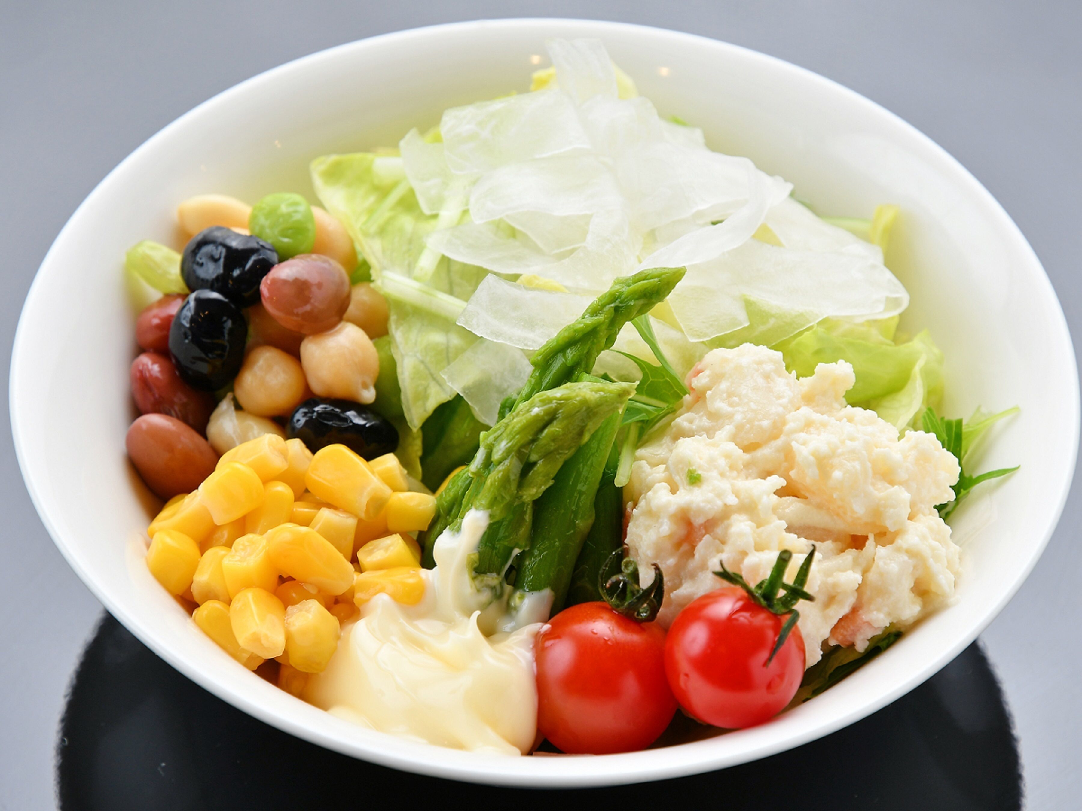 A bowl of salad with various vegetables and fruits.