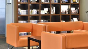 Una biblioteca amb seients taronja i una gran estanteria.
