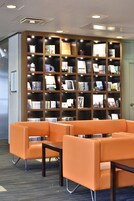 Una biblioteca con asientos naranjas y una estantería grande.