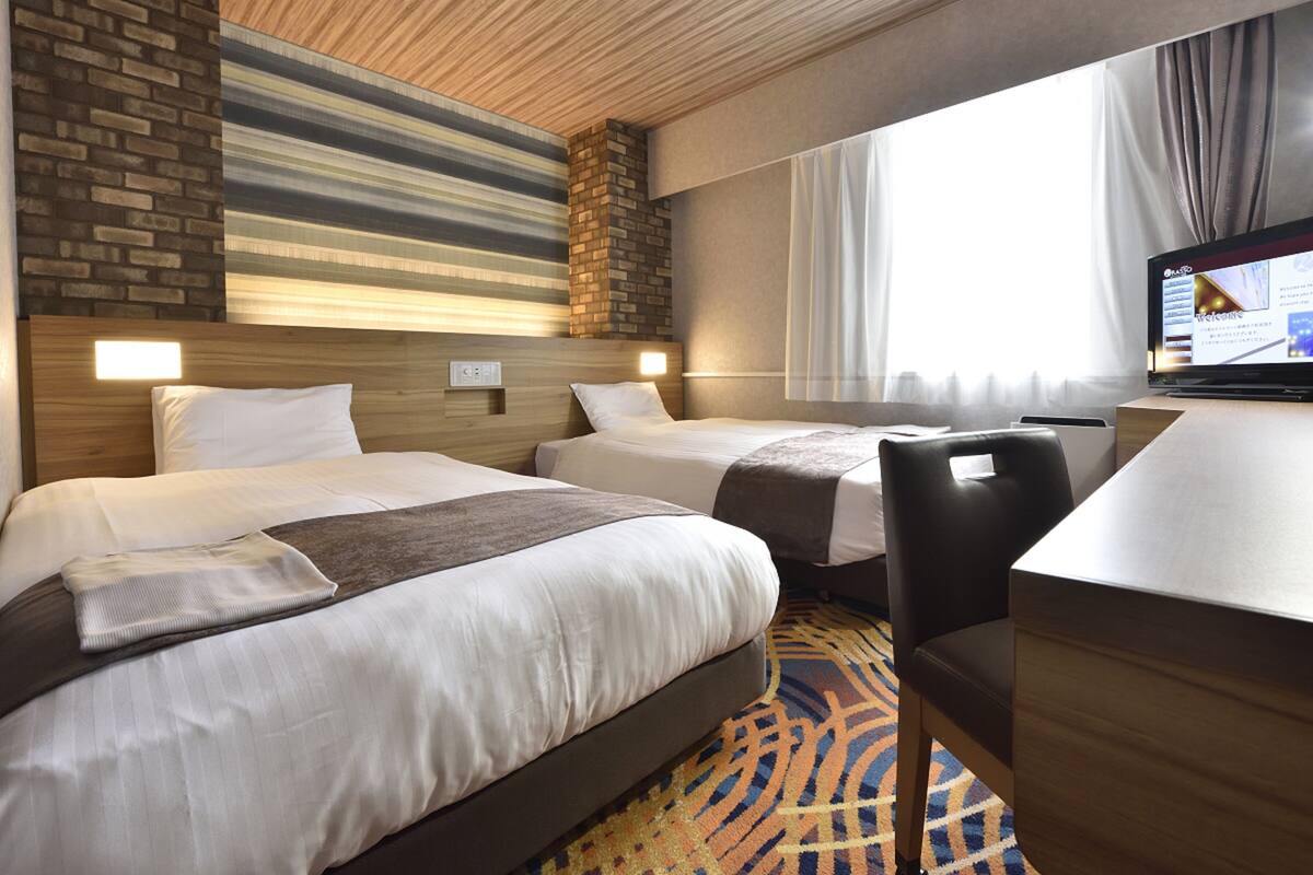 Ett hotellrum med två sängar, ett skrivbord och en TV.