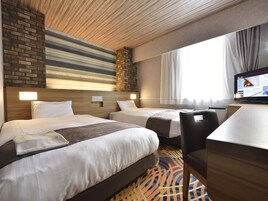 Una habitación de hotel con dos camas, un escritorio y una televisión.