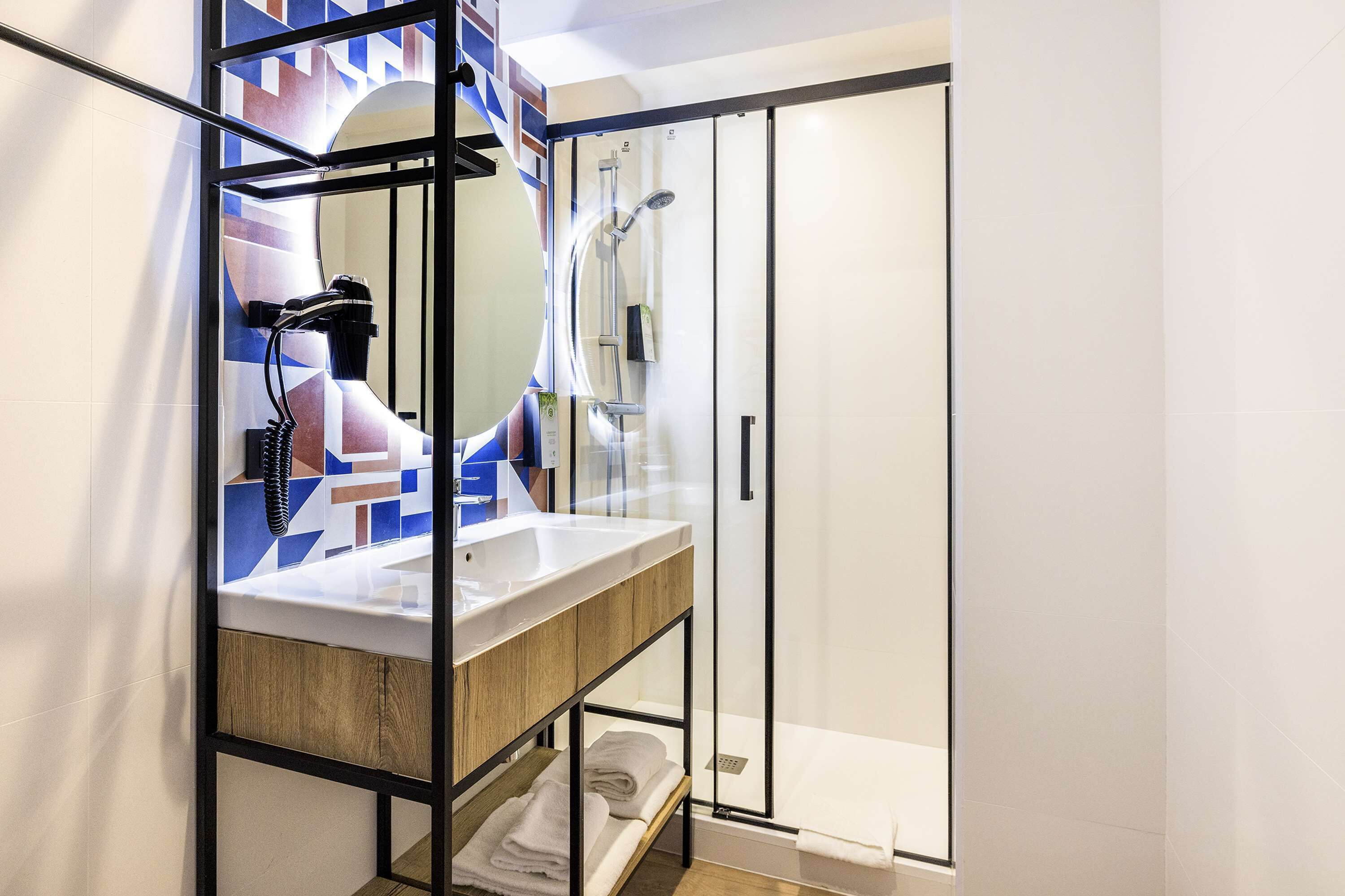 A modern bathroom with a glass shower enclosure, a wooden vanity with a sink, and a large mirror.