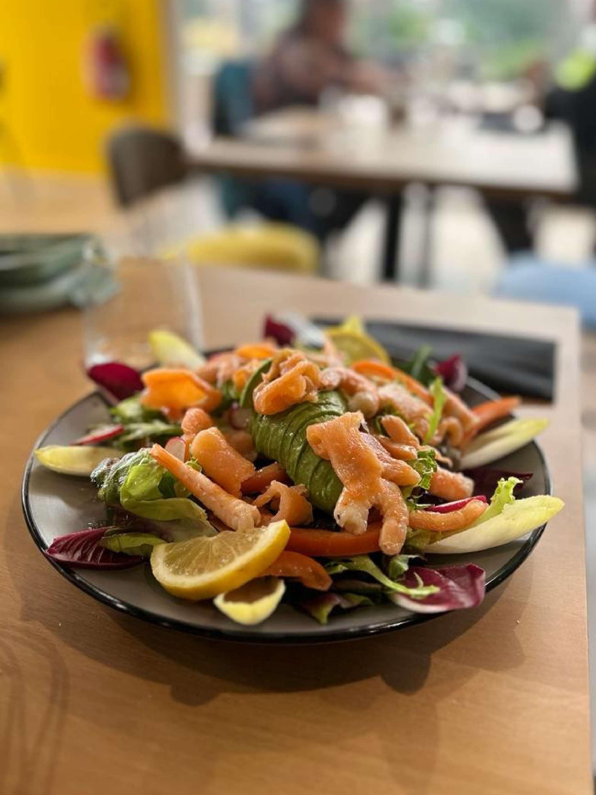A plate of food with various vegetables and a slice of lemon on a table.
