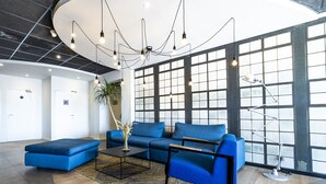 Un vestíbulo moderno con un sofá azul, una mesa de centro y una lámpara de escritorio.