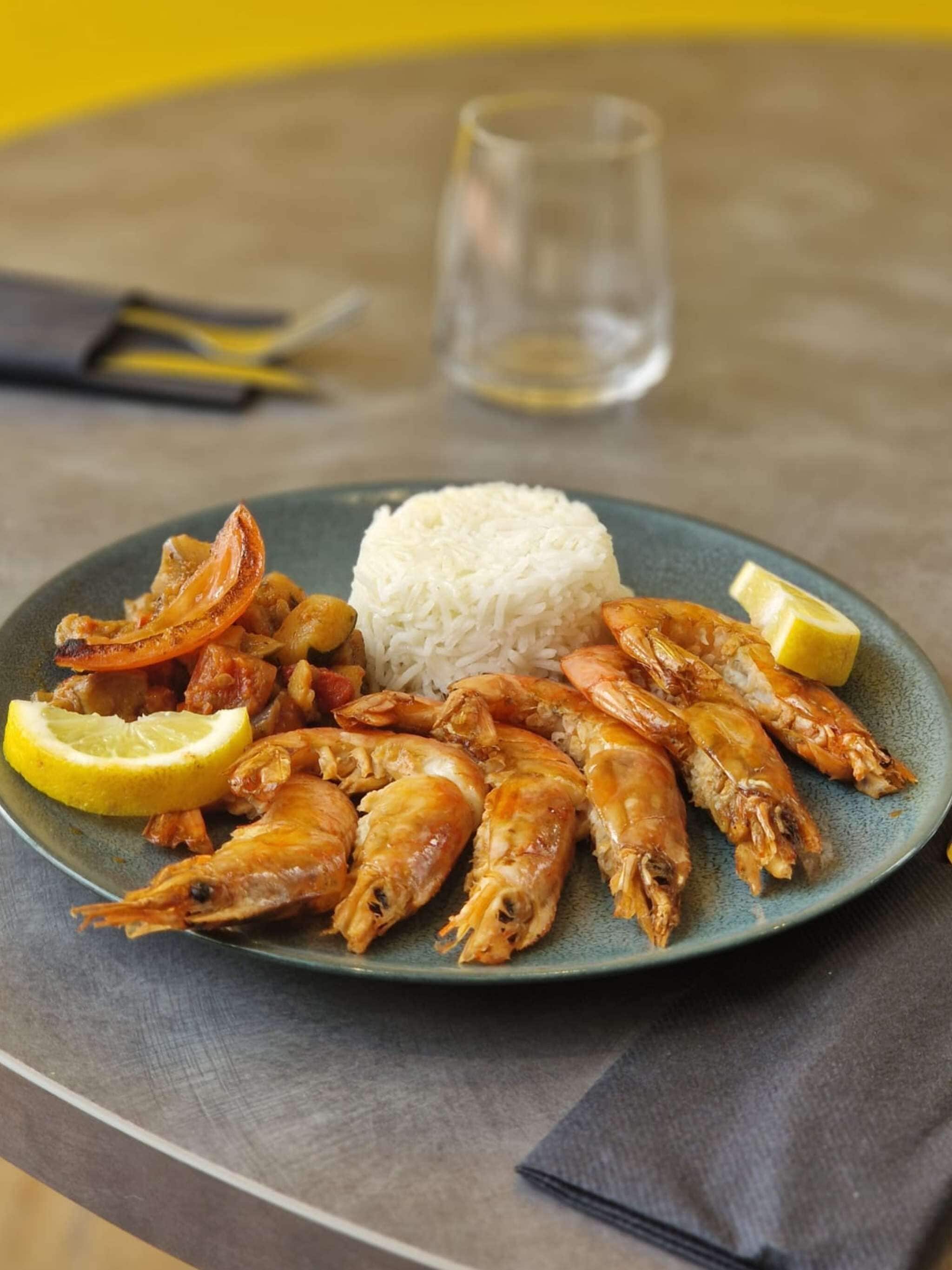 Un plato de camarones cocidos y arroz sobre una mesa.
