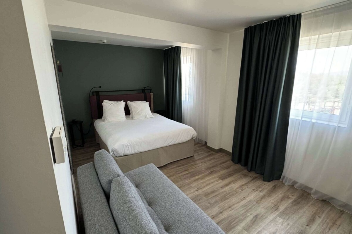 Una habitación de hotel moderna con una cama, un sofá y vistas al exterior.