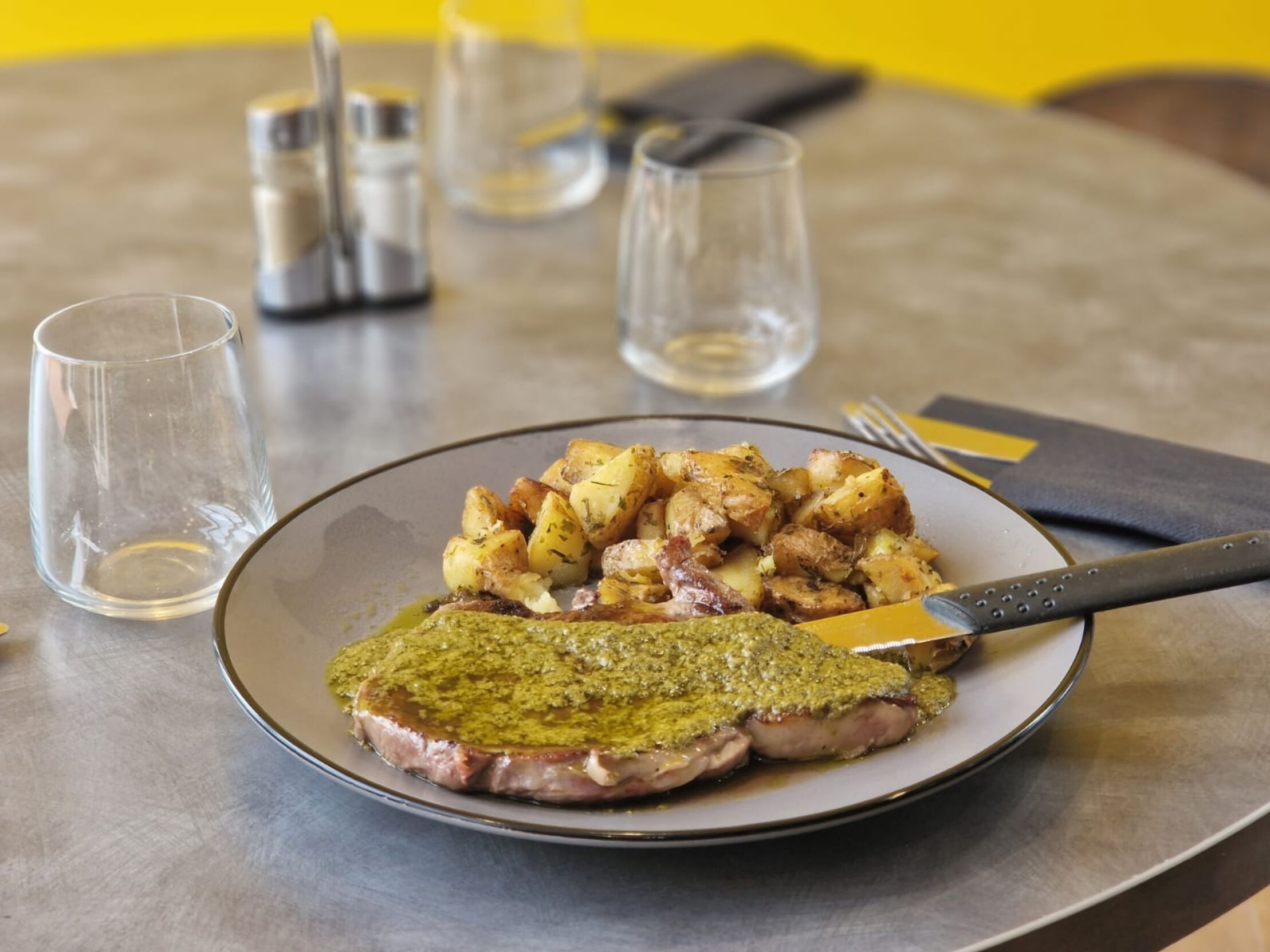 Une assiette avec un steak et des pommes de terre rôties, posée sur une table.