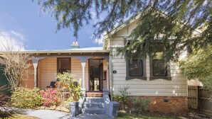 A two-story house with a front porch, a brick foundation, and a well-maintained garden. - Hotel Blue & Cottages, Katoomba (Katoomba)