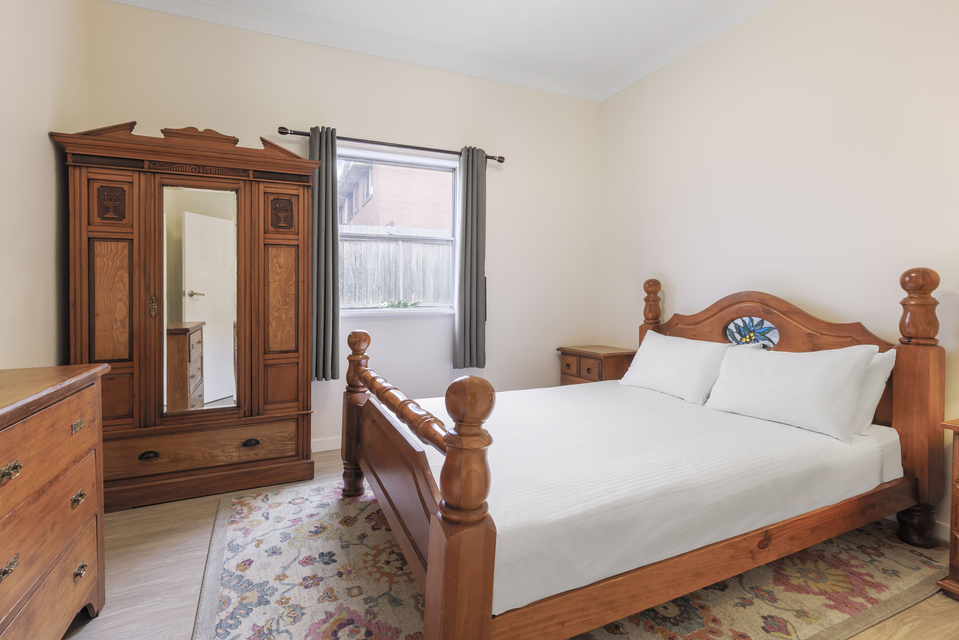 A bedroom with a wooden bed, a dresser, and a large mirror.