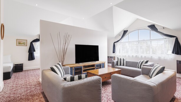 A modern living room with two grey sofas, a wooden coffee table, and a flat-screen TV. - Hotel Blue & Cottages, Katoomba (Katoomba)