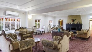 A spacious living room with multiple armchairs, a fireplace, and a large window with curtains. - Hotel Blue & Cottages, Katoomba (Katoomba)