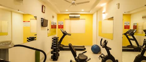 A gym with exercise equipment, a ceiling fan, and mirrors on the walls.