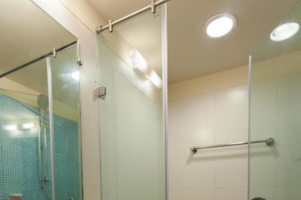 A bathroom with a glass shower enclosure, a white sink, and a mirror.