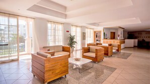 A spacious lobby with wooden furniture, large windows, and a reception desk. - Aqua Mar Albufeira (Albufeira)