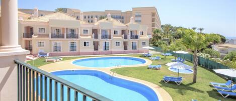 A hotel with a pool area, multiple balconies, and a view of the sea.